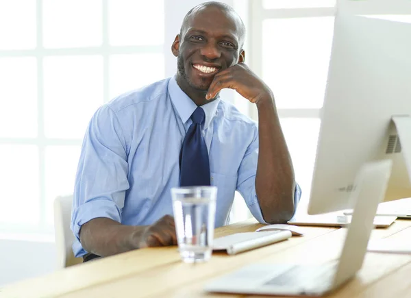 Empresário afro-americano no fone de ouvido trabalhando em seu laptop — Fotografia de Stock