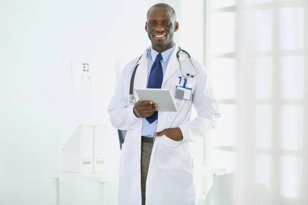 Mężczyzna czarny lekarz pracownik z tablet stojący w szpitalu — Zdjęcie stockowe