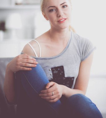 Genç ve güzel bir kadın odasında kanepede oturuyor.