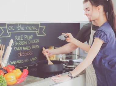 Bir çift evdeki mutfaklarında birlikte yemek pişiriyor.