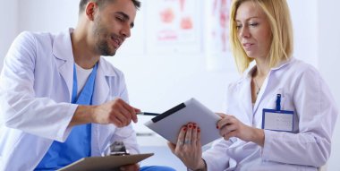 Yakışıklı doktor genç bayan doktorla konuşuyor ve ofisinde otururken notlar alıyor..