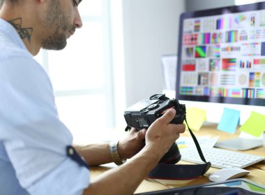 İnternette çalışırken bilgisayarın ve dizüstü bilgisayarın önünde grafik stüdyosunda oturan genç tasarımcının portresi.
