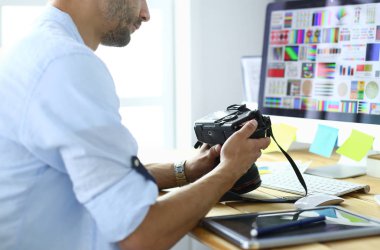 İnternette çalışırken bilgisayarın ve dizüstü bilgisayarın önünde grafik stüdyosunda oturan genç tasarımcının portresi.