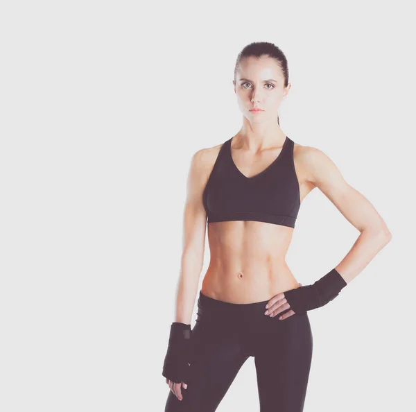 Muscular young woman posing in sportswear against black background. — Stock Photo, Image