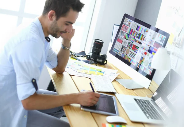 Porträt eines jungen Designers, der im Grafikstudio vor Laptop und Computer sitzt, während er online arbeitet. — Stockfoto