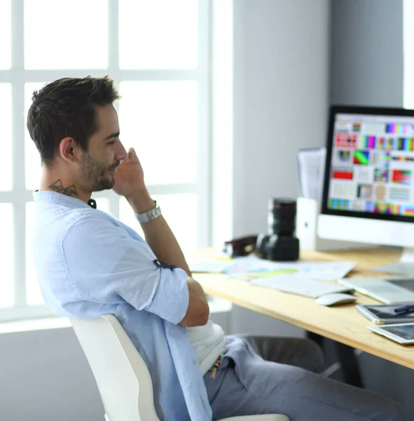 Ritratto di giovane designer seduto allo studio grafico di fronte a laptop e computer mentre lavora online. — Foto Stock