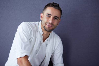 Gri arka planda yalnız oturan genç iş adamı.