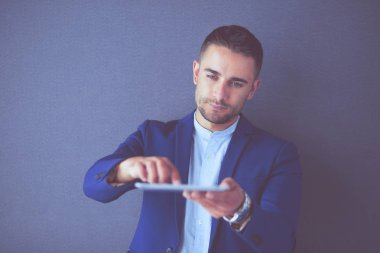 Gri arka planda yalnız oturan genç iş adamı.