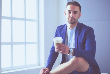 Gri arka planda yalnız oturan genç iş adamı.