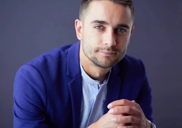 Joven empresario sentado aislado sobre fondo gris. —  Fotos de Stock