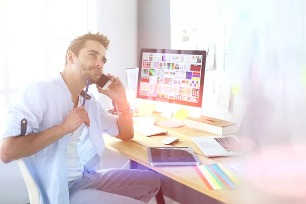 Porträt eines jungen Designers, der im Grafikstudio vor Laptop und Computer sitzt, während er online arbeitet. — Stockfoto