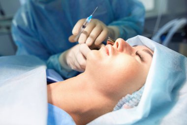 Ameliyat odasında arka planda erkek cerrah var.