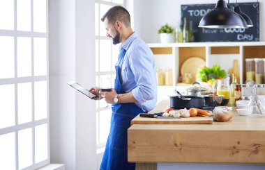 Dijital tablet ve yemek pişirme tarifine uyan bir adam evdeki mutfakta lezzetli ve sağlıklı yemekler pişiriyor.