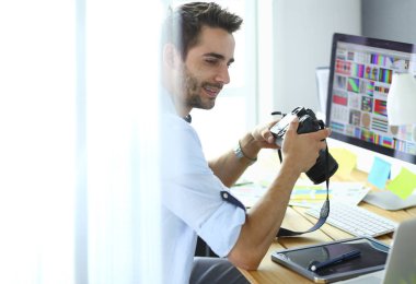 İnternette çalışırken bilgisayarın ve dizüstü bilgisayarın önünde grafik stüdyosunda oturan genç tasarımcının portresi.