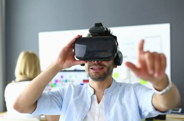 Genç erkek yazılım programcısı ofiste üç boyutlu sanal gerçeklik gözlükleriyle yeni bir uygulama test ediyor..