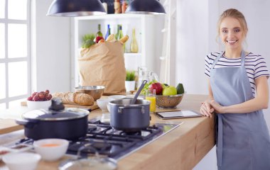 Evdeki mutfakta yemek pişiren güzel genç bir kadın.
