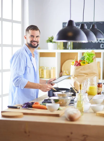 Homem seguindo receita em tablet digital e cozinhar comida saborosa e saudável na cozinha em casa — Fotografia de Stock