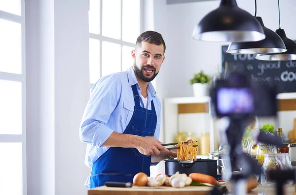 Hombre sosteniendo bolsa de papel llena de comestibles en el fondo de la cocina. Compras y concepto de comida saludable — Foto de Stock