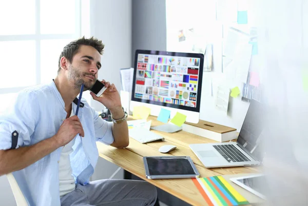 Porträt eines jungen Designers, der im Grafikstudio vor Laptop und Computer sitzt, während er online arbeitet. — Stockfoto