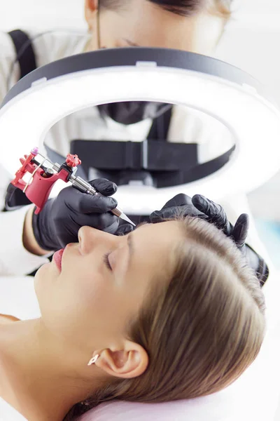 Mikroostrza brwi pracują w salonie piękności. Kobieta z przyciemnionymi brwiami — Zdjęcie stockowe