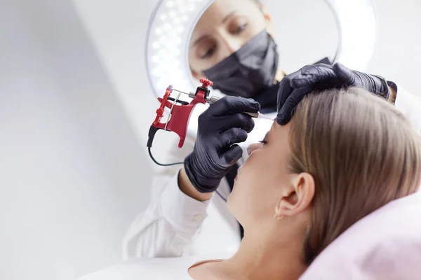 Microblading eyebrows work flow in a beauty salon. Woman having her eye brows tinted — Stock Photo, Image