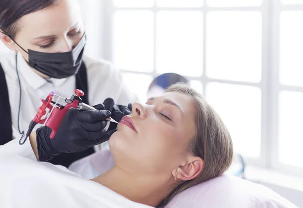 Cosmetologist aplicando a composição permanente nas sobrancelhas — Fotografia de Stock