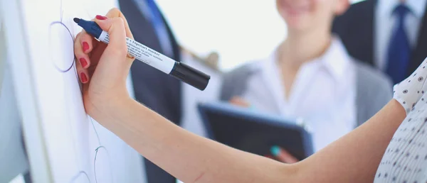 Businesswoman writing on flipchart while giving presentation to colleagues in office — Stock Photo, Image