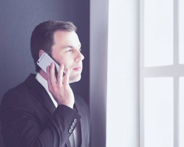 Modern ofiste cep telefonuyla konuşan yakışıklı iş adamı..