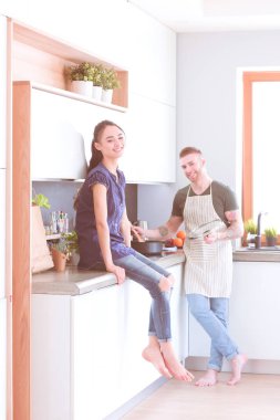 Bir çift evdeki mutfaklarında birlikte yemek pişiriyor.