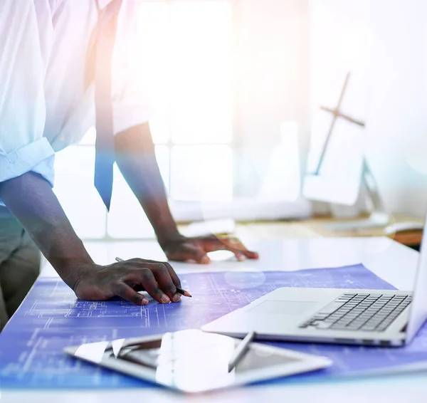 Arquitecto afroamericano trabajando con computadoras y planos en la oficina —  Fotos de Stock