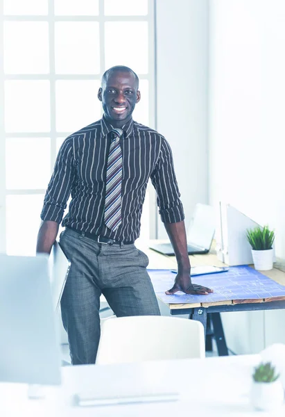 Ofiste bilgisayar ve planlarla çalışan Afrikalı Amerikalı bir mimar. — Stok fotoğraf