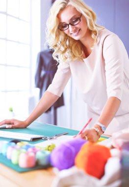 Moda tasarımcısı kadın stüdyoda tasarımları üzerinde çalışıyor.