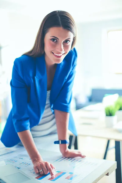 Retrato de una hermosa mujer de negocios de pie cerca de su lugar de trabajo. — Foto de Stock