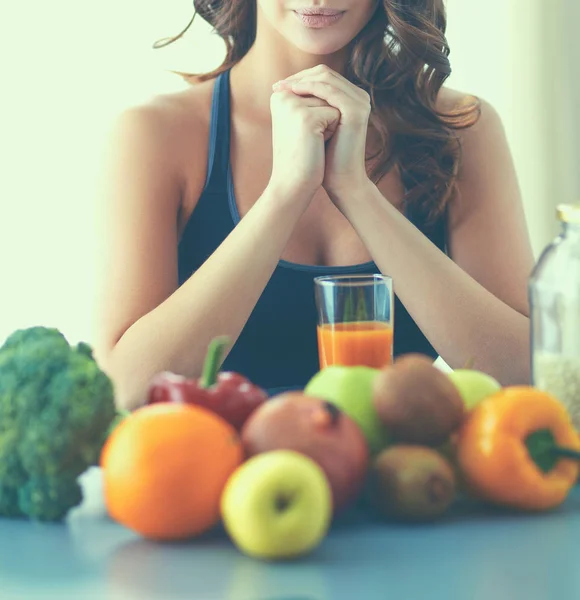 Menina sentada na cozinha na mesa com suco de frutas e copos — Fotografia de Stock