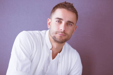 Gri arka planda yalnız oturan genç iş adamı