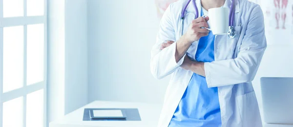 Young doctor with coffee cup in medical office — Stock Photo, Image