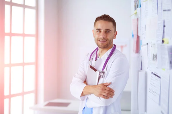 Jovem e confiante retrato médico masculino em pé no consultório médico — Fotografia de Stock