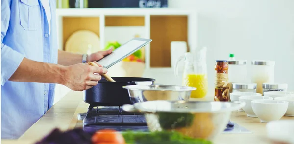 Férfi következő recept digitális tabletta és főzés ízletes és egészséges étel a konyhában otthon — Stock Fotó