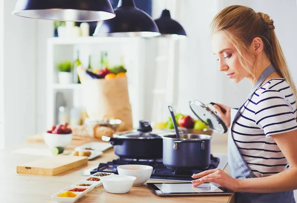 Mujer joven usando una tableta para cocinar en su cocina — Foto de Stock