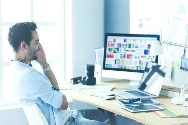 Porträt eines jungen Designers, der im Grafikstudio vor Laptop und Computer sitzt, während er online arbeitet. — Stockfoto