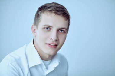 Gri arka plan üzerinde oturan gülümseyen genç adam portresi. Genç adam portresi