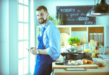 Mutfak arka planında poşet dolusu erzak tutan adam. Alışveriş ve sağlıklı gıda konsepti