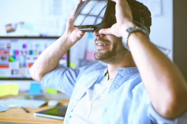 Genç erkek yazılım programcısı ofiste üç boyutlu sanal gerçeklik gözlükleriyle yeni bir uygulama test ediyor..