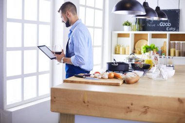 Dijital tablet ve yemek pişirme tarifine uyan bir adam evdeki mutfakta lezzetli ve sağlıklı yemekler pişiriyor.