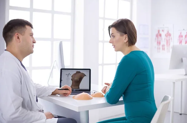 Arzt zeigt junge Patientin ihre Brust in seinem Büro im Krankenhaus — Stockfoto