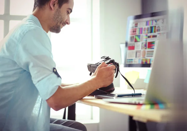 Retrato del joven diseñador sentado en el estudio gráfico frente a la computadora portátil y el ordenador mientras trabaja en línea. — Foto de Stock