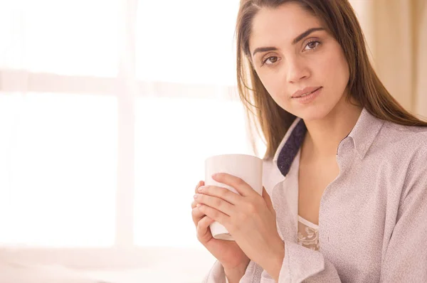 Mulher sentada na cama lendo um livro e tomando café da manhã — Fotografia de Stock