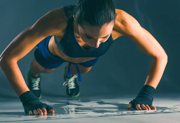 Junge Frau macht Liegestütze auf einer Matte. — Stockfoto