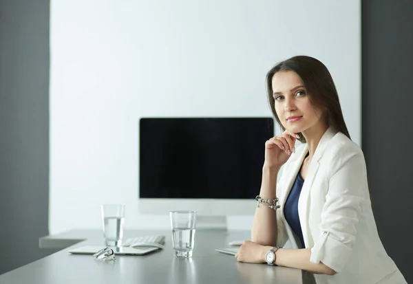 Pohled na usmívající se obchodní ženu, která sedí u stolu s laptopem a dívá se na kameru v kanceláři — Stock fotografie