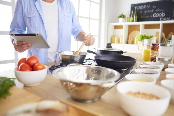 Dijital tablet ve yemek pişirme tarifine uyan bir adam evdeki mutfakta lezzetli ve sağlıklı yemekler pişiriyor. — Stok fotoğraf